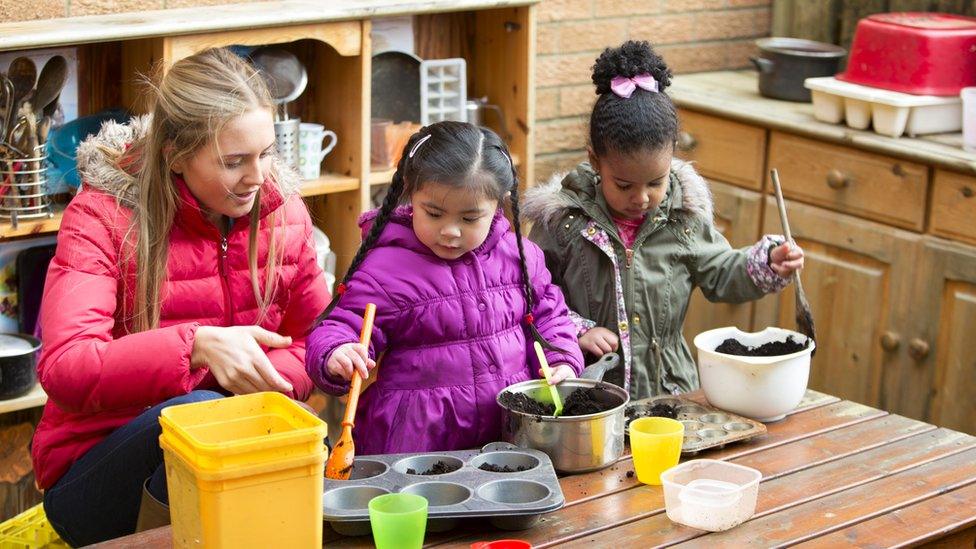 A nursery worker with two pre-schoolers