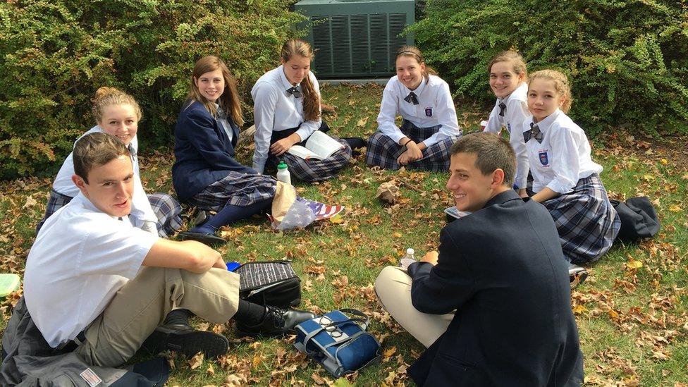 Schoolchildren sitting on the grass in a circle