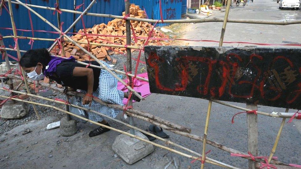 A woman in a designated red zone pushes through a barricade