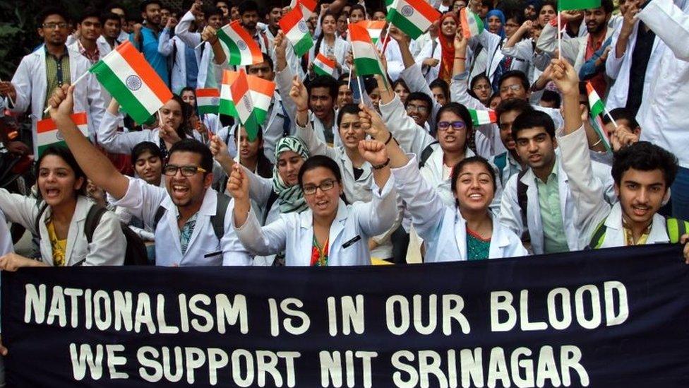 Indian medical college students hold placard and shout slogans against the alleged police action on outstation students at the National Institute of Technology (NIT) Srinagar during protest demonstration in Jammu,