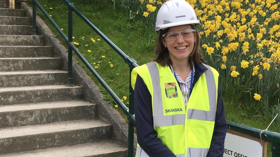 Skanksa employee Kate Young standing by some railings wearing a hard hat and high-vis jacket