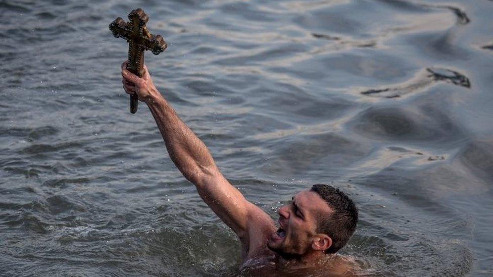 Greek Orthodox swimmer Nico Solis holds up a wooden cross after retrieving it from the Bosporus river during the blessing of the water ceremony, as part of celebrations of the Epiphany day at the Church of Fener Orthodox Patriarchate (6 January 2015)