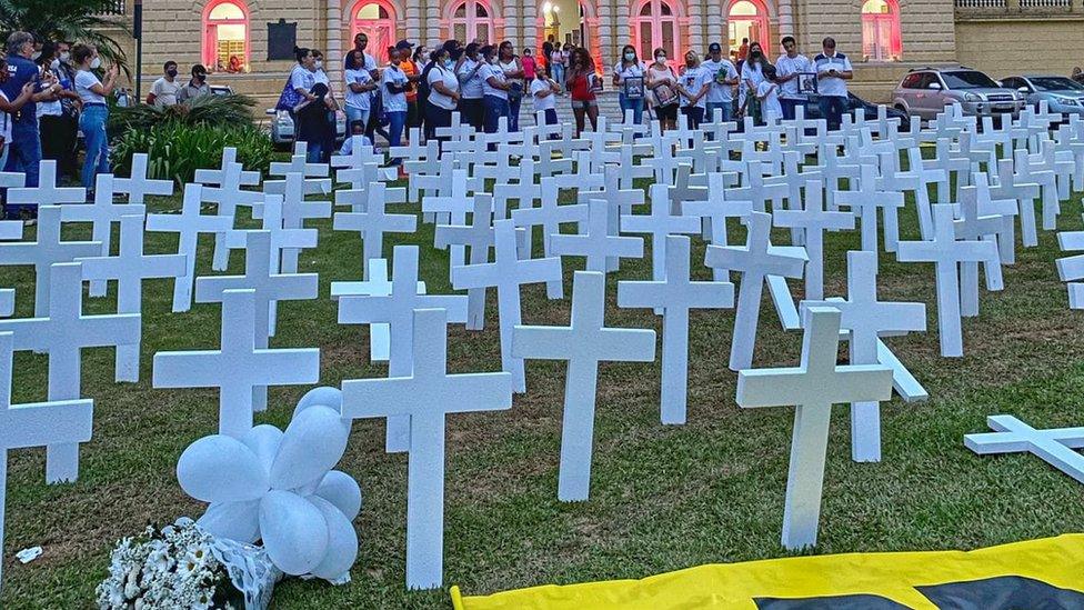 A group of people standing in front of white crosses in a memorial