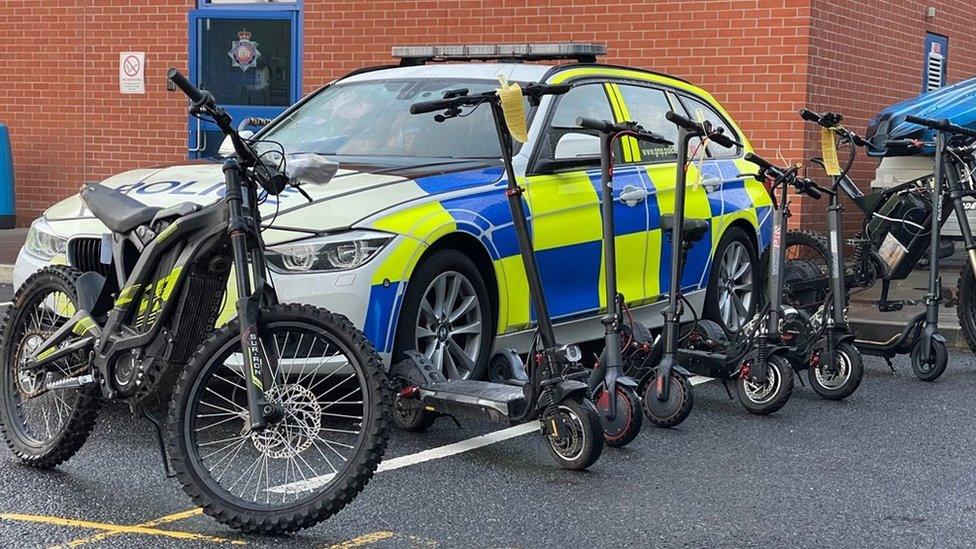 Seized e-scooters in front of a police car