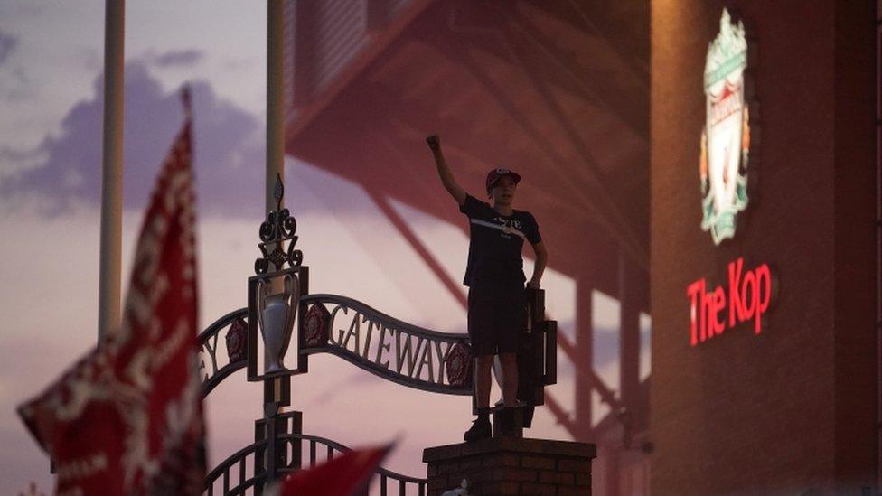 Boy standing on gates outside Anfield