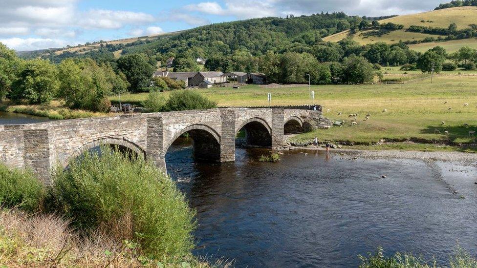 An old stone arched bridge over The River Dee flowing through the Vale of Llangollen, Carrog, Denbighshire