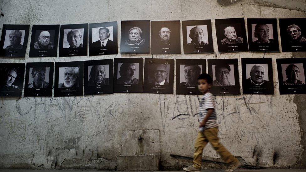 Boy walks past photos of political prisoners at the Santiago Stadium in Chile