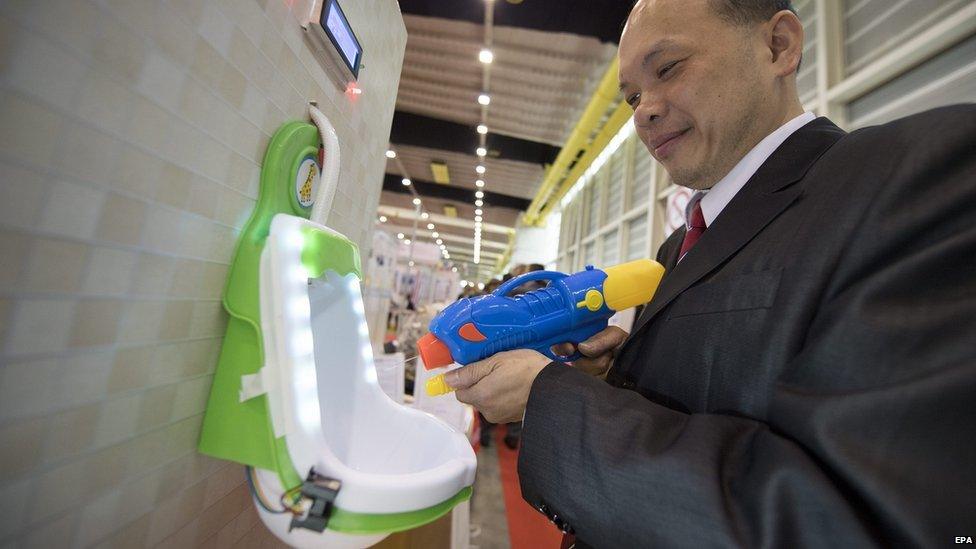 Man squirting a water gun into a urinal