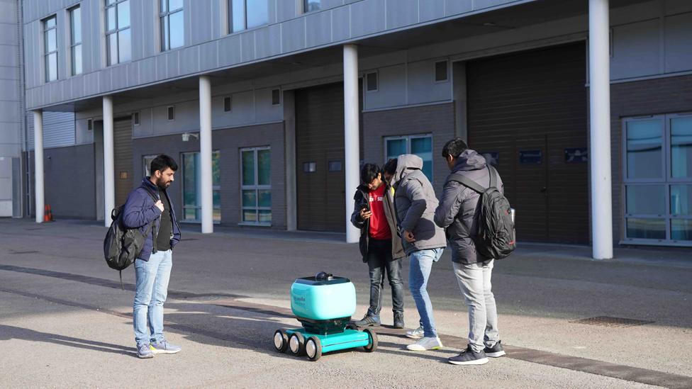 Students standing by a robot