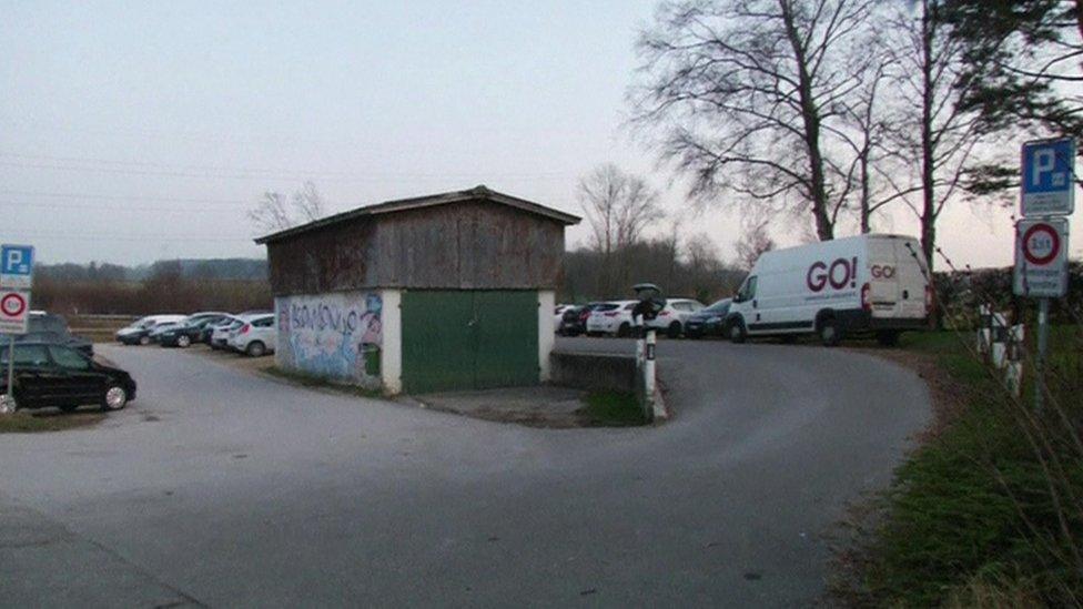 A car park area, with a barn-like structure in the middle