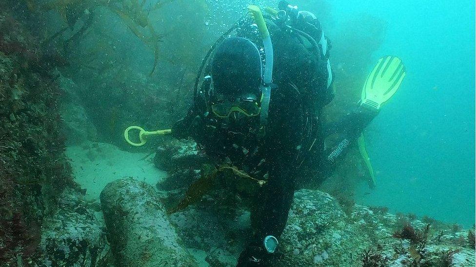 Diver David Gibbins with a cannon on the wreck site in 2021