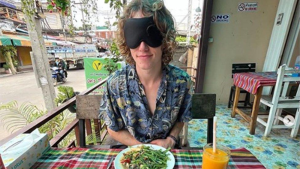 Ed Smith, blindfolded, sitting at a table with a plate of food in front of him