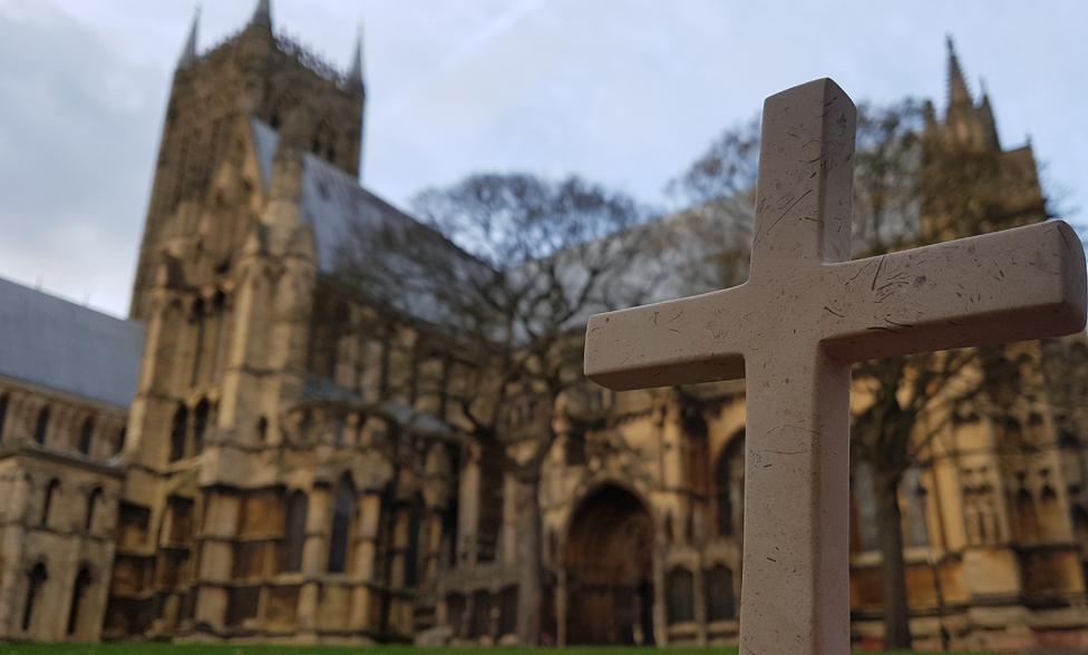 A cross outside with Lincoln Cathedral in the background