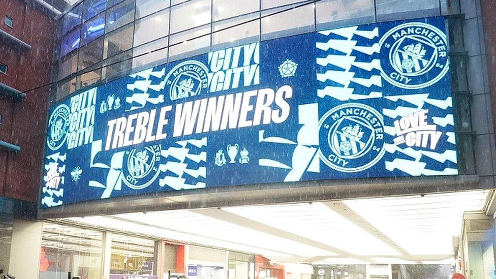 Sign outside Manchester Arndale proclaiming City as treble winners