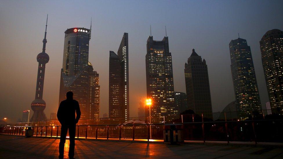 A man looks at the Pudong financial district of Shanghai in November 2013