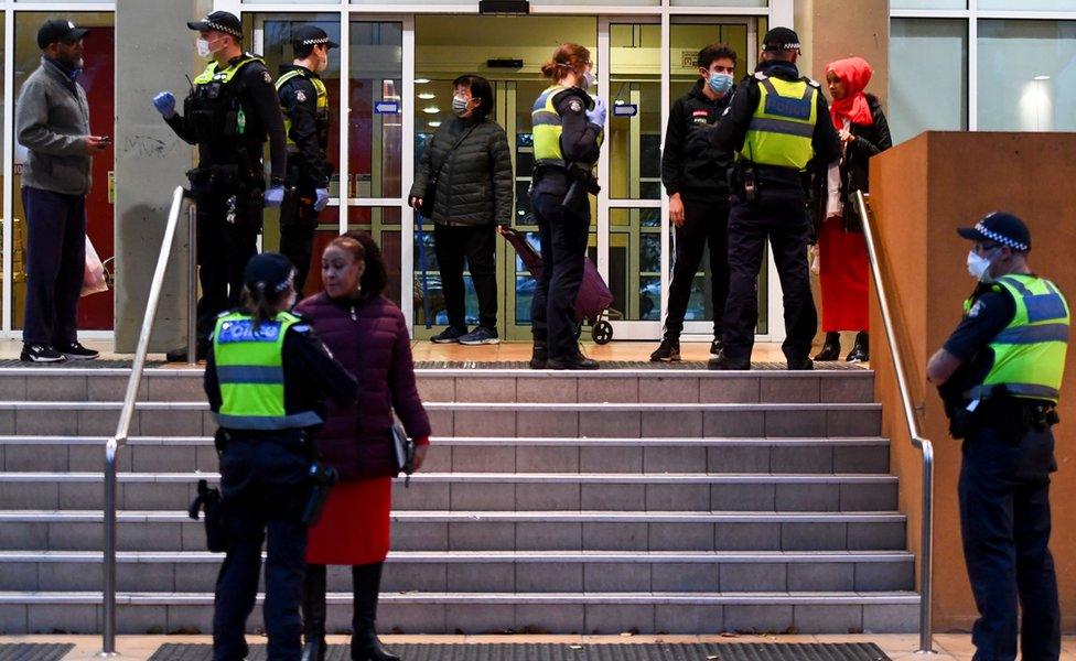 Police officers speaking to residents outside the entrance to one of the housing tower blocks