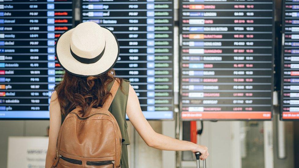 Woman looking at airport departure board