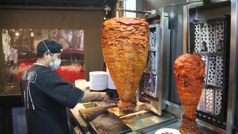 Man carves trompo meat