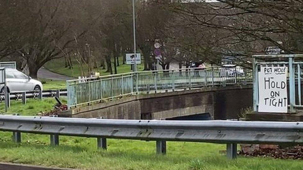 Sign on railings in the middle of a roundabout which says "hold on tight"