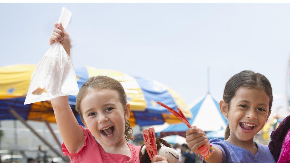 children at a funfair holdig prizes including a goldfish