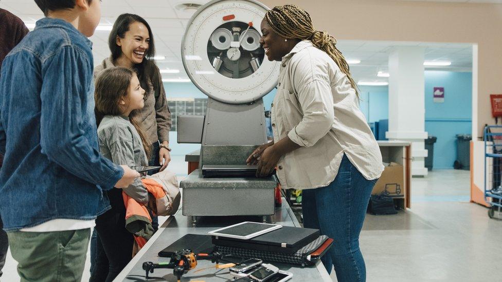 Adult woman explaining to a child about recycling phones, old parts on the table