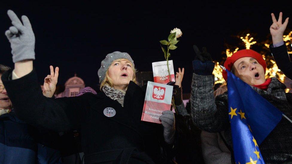 Polish protesters against a controversial new judicial reform law hold copies of the constitution and EU flags in Warsaw. File photo