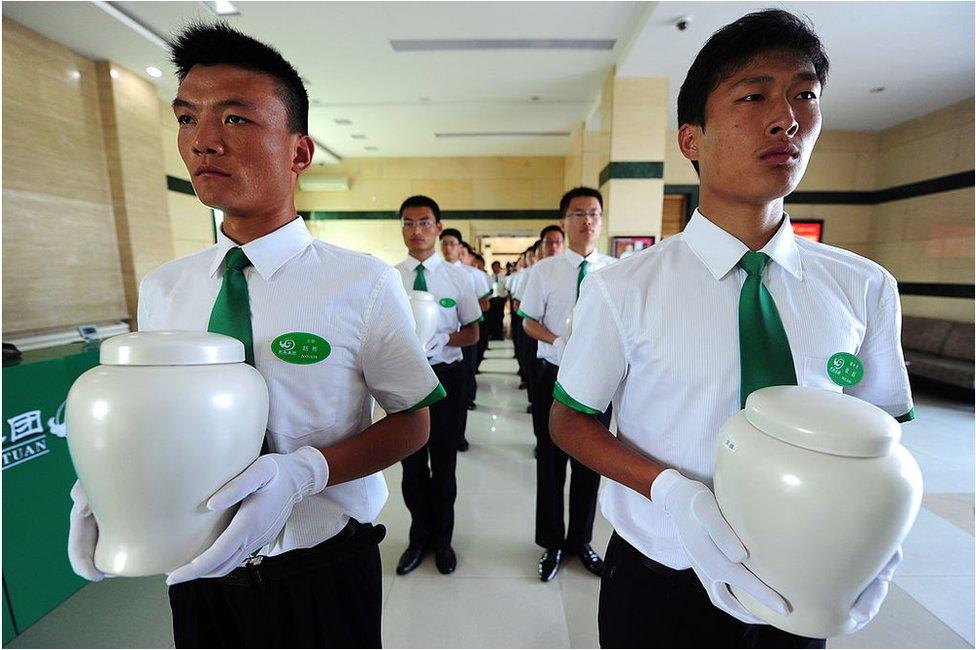 Attendants carry biodegradable urns at a cemetery in Tianjin, northern China, for a collective eco-burial on 20 July 2010.