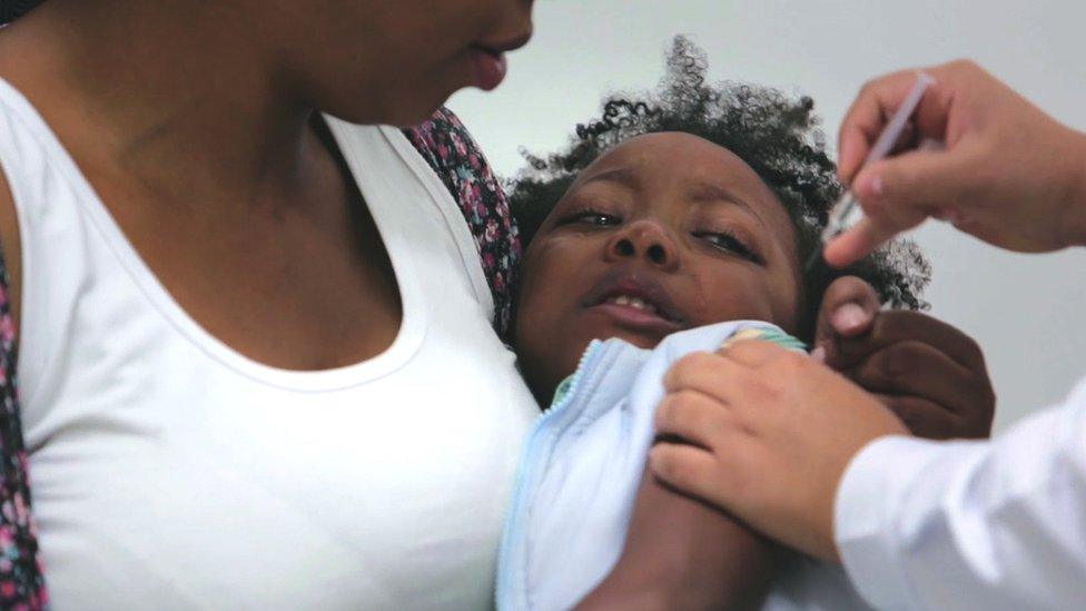 Toddler in mother's arms being vaccinated