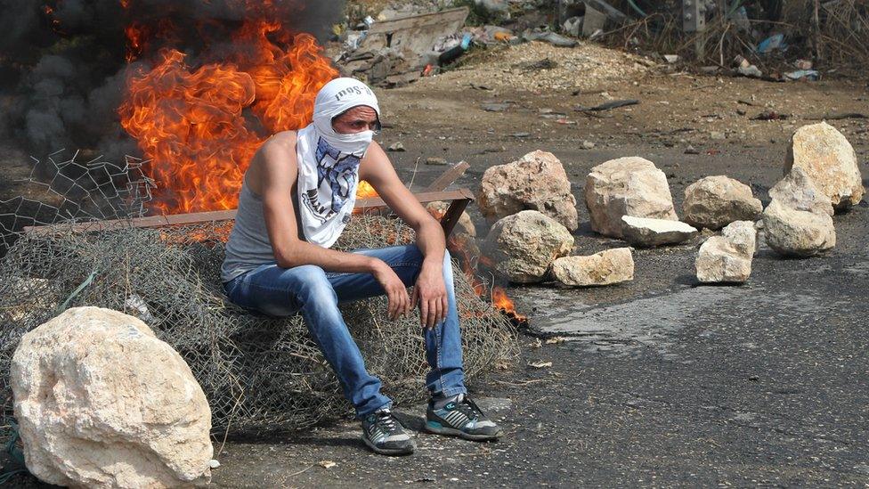 A Palestinian student from Palestine Polytechnic University sits during a protest against Israel near the Jewish settlement of Beit Hagai, October 2015