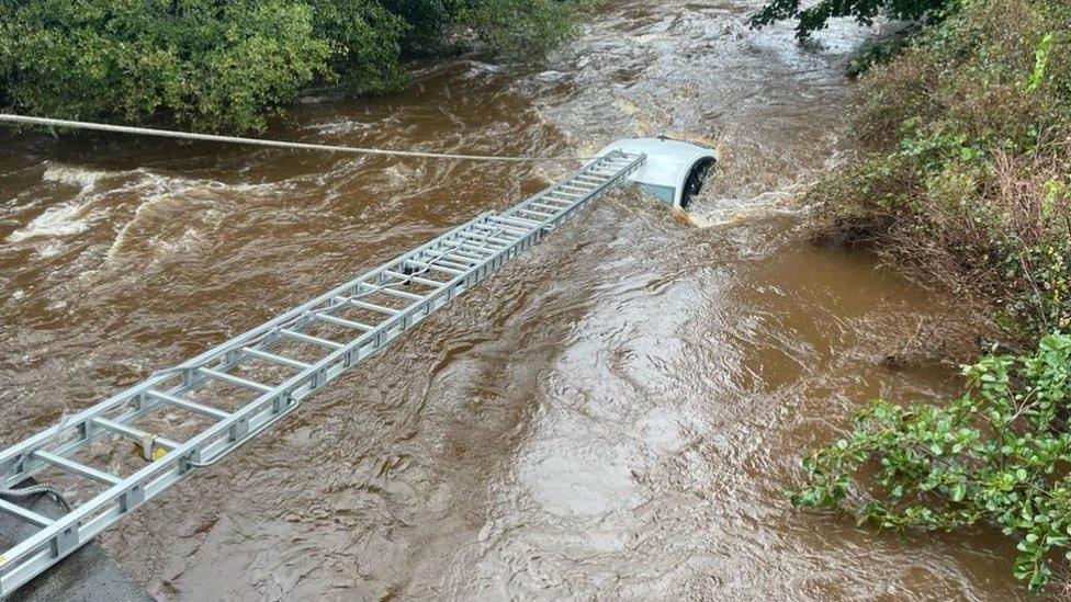 Firefighters used a long ladder to reach the vehicle during the rescue