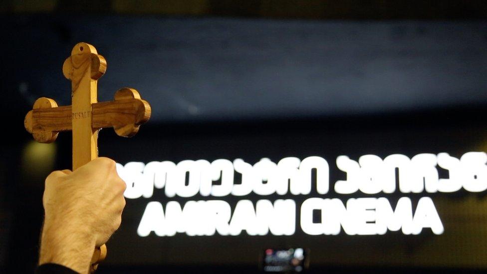 A cross is held up outside the cinema showing the film And Then We Danced