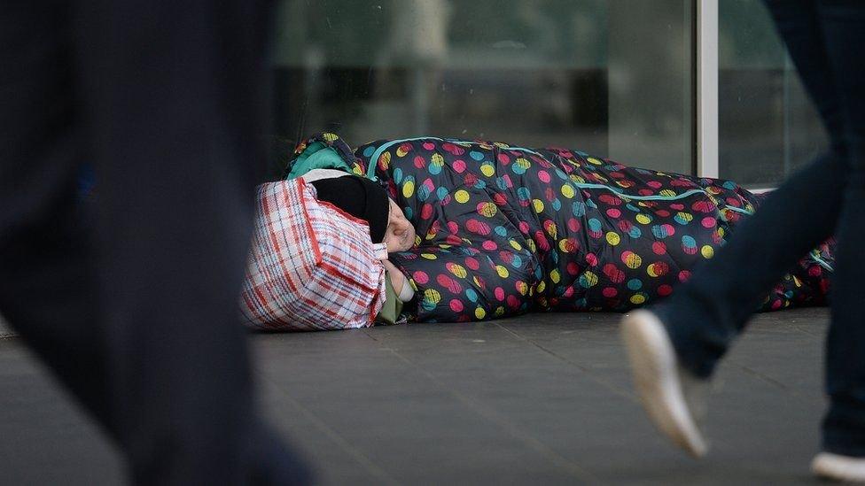 A man sleeping on the street in a sleeping bag