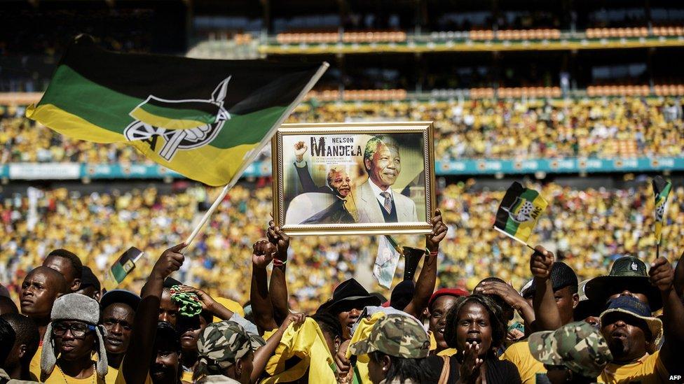 Supporters of South Africa's ruling African National Congress sing and dance while holding a framed poster of late anti-apartheid leader Nelson Mandela during the final ANC election campaign rally at Soccer City stadium in Johannesburg on May 4, 2014.