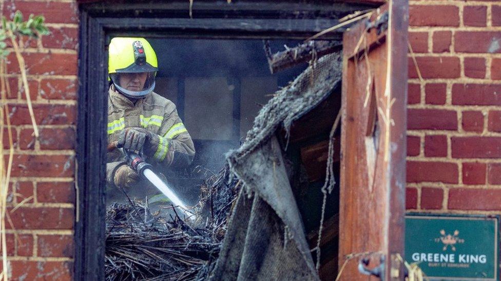 Firefighter tackling hotspots after a pub fire