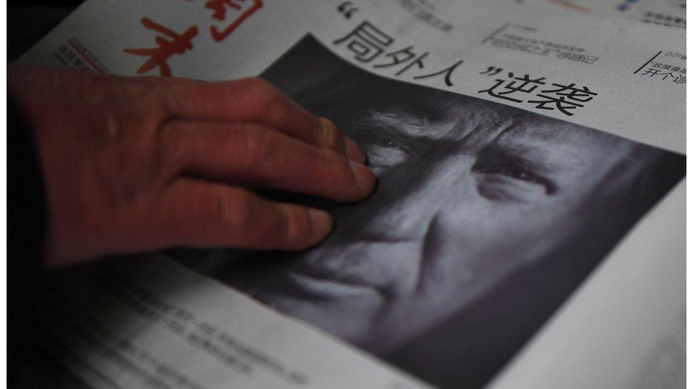 Shows a man buying a newspaper featuring a photo of US President-elect Donald Trump, the day after the US election, at a news stand in Beijing on November 10, 2016. The headline reads "Outsider strikes back".