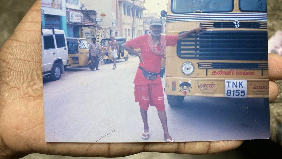 Om Prakash's son holds up a photo of his father from the family album