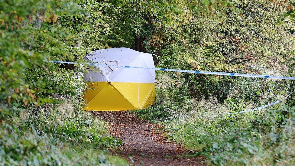 A tent behind a police cordon in woodland