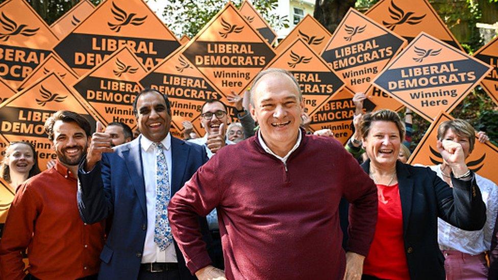 Liberal Democrat leader Ed Davey with party members waving placards