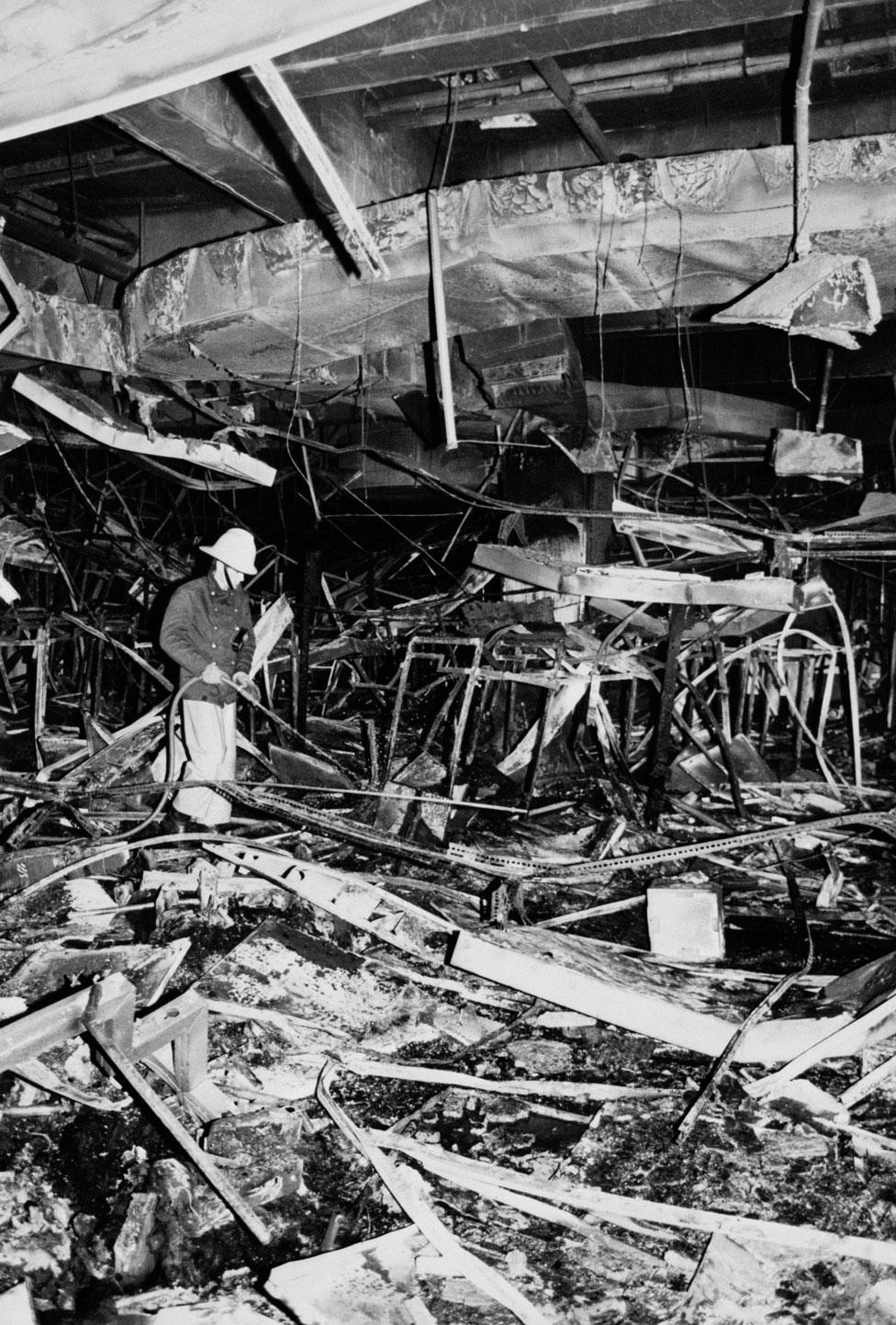 A fireman hoses down the remains of a gutted building