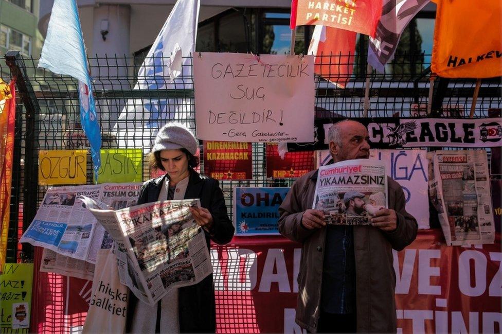 A protester holds a copy of the Turkish daily newspaper "Cumhuriyet" next to a woman reading it during a demonstration outside the newspaper"s headquarters in Istanbul on November 2, 2016.