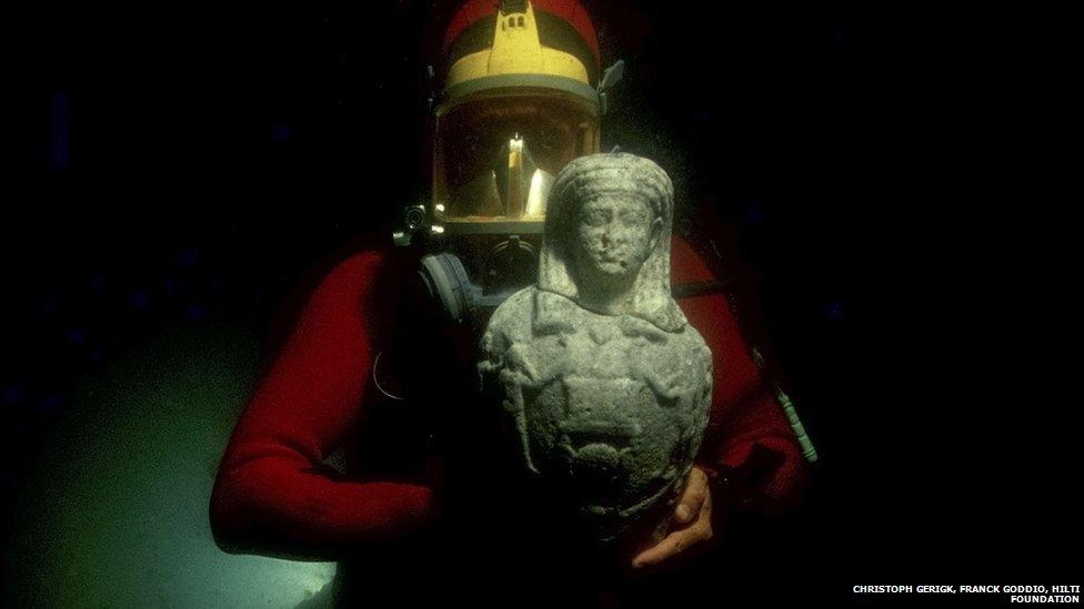 A diver discovers a statue of Osiris. The god Osiris represents regeneration. The decoration on the statue represents water, the source of life.