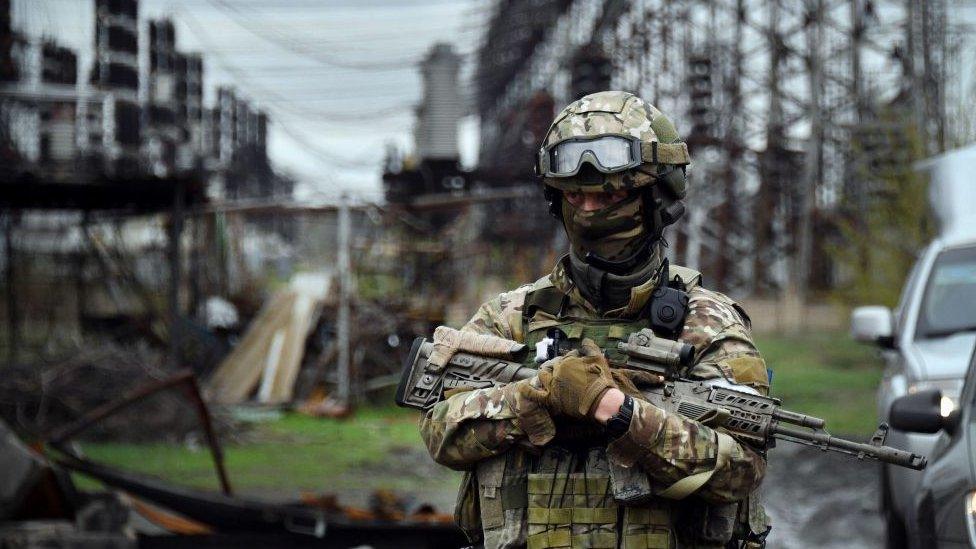 a russian soldier standing outside a power plant in the Luhansk region