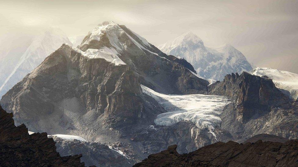 Mount Everest's snowy summit surrounded by peaks with snow and bare rock