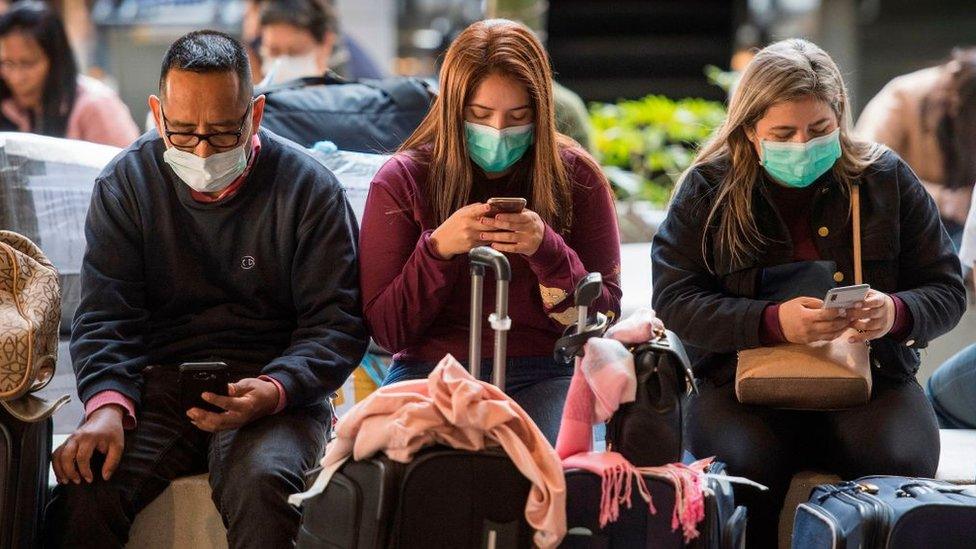 Passengers wear face masks to protect against the spread of the Coronavirus as they arrive on a flight from Asia at Los Angeles Airport