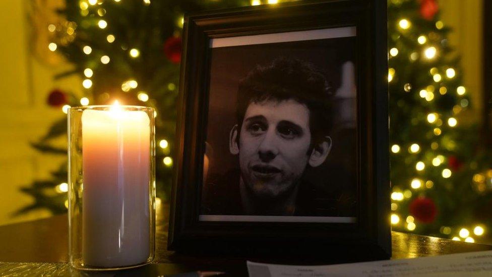 A candle burning next to a photograph of Shane MacGowan