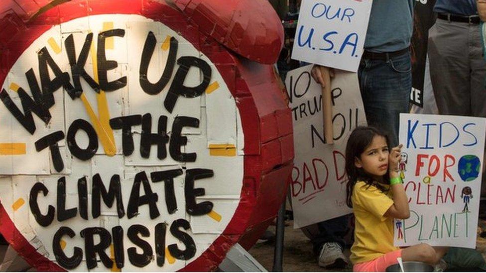 sign made to look like an alarm clock, that says "Wake up to climate change"