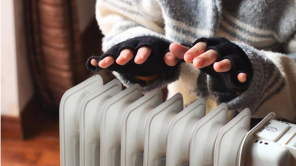 Person warming hands over portable radiator