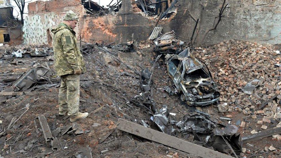 Soldier looks at ruins of Mariupol.