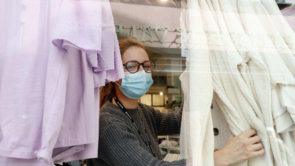 A shop worker wearing a mask as she arranges a window display