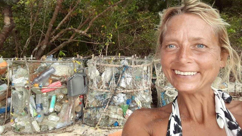 Natalie Poole in front of large containers of waste.